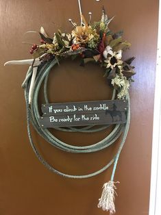 a wreath hanging on the door with a sign that says if you drink in the saddle, don't worry for the ride