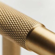 a close up view of a gold colored metal handle on a white background with the focus on the top part of the handle