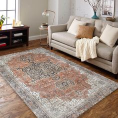 a living room filled with furniture and a rug on top of a hard wood floor