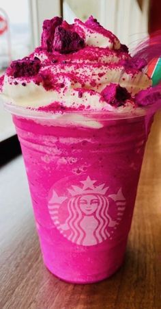 a pink drink with whipped cream and toppings on the top is sitting on a table