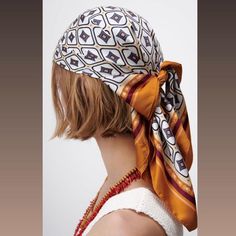 a woman wearing a head scarf with an orange and white design on the top of her head