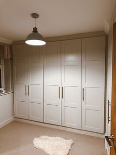 an empty room with white cupboards and a sheepskin rug on the floor in front of it