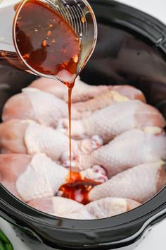 chicken being poured into an air fryer with broth in the middle and green onions on the side