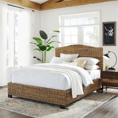 a bed with white linens and pillows in a room next to a wooden floor