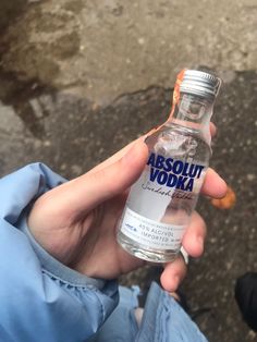 a person holding a bottle of vodka in their left hand, with the label absolut vodka on it