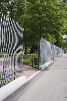 a long metal fence next to a sidewalk