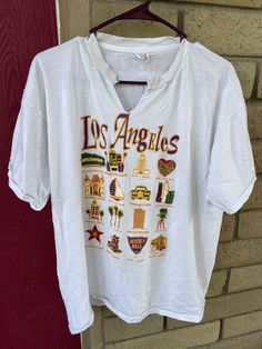 a t - shirt hanging on a brick wall with the word los angeles printed on it