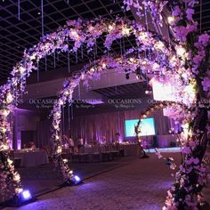 an archway decorated with purple flowers and lights