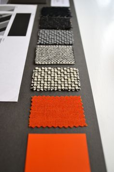 several different color swatches are arranged on a black and white table top with orange accents