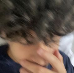 a blurry photo of a person with his hand on his face and hair blowing in the wind