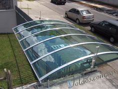 an upside down glass roof on the side of a building with cars parked in front of it