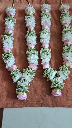 flowers arranged in the shape of letter v on a brown cloth with gold chains hanging from it