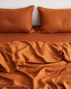 a bed with two pillows on top of it and an orange comforter in the middle