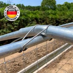 a close up of a fence with a german flag sticker on the gate and trees in the background