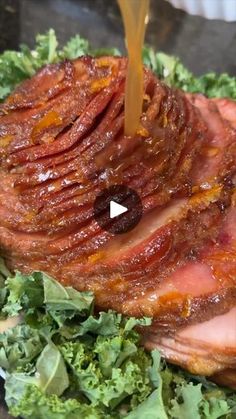 the ham is being drizzled with sauce on it's side while sitting on a bed of lettuce