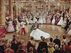 a group of people standing around each other in front of a large room with chandeliers