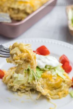 a fork is lifting up some food from a white plate with other dishes in the background