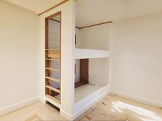 an empty room with white walls and wooden stairs leading to the second floor bed area