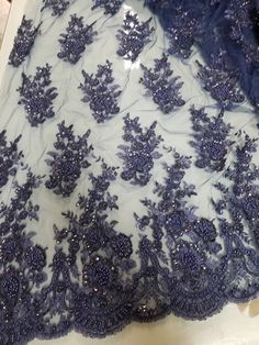 the back of a dress with blue flowers and beads on it, sitting on a table