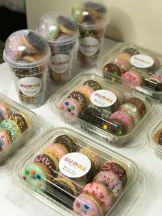 several plastic containers filled with donuts on top of a white tablecloth and covered in sprinkles