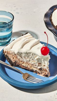 a piece of pie on a blue plate with a fork and glass of water next to it