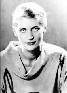 an old black and white photo of a woman with scissors on her shoulder, looking at the camera