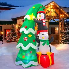 an inflatable christmas tree with two snowmen next to it and a lit up penguin