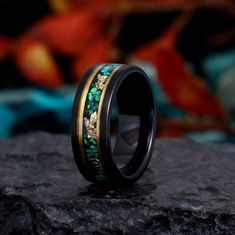 a wedding band with green and gold inlays