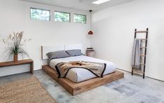 a bedroom with a large bed and two windows on the wall above it, along with a rug