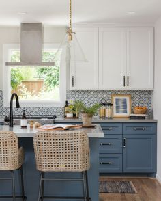 a kitchen with blue cabinets and wicker chairs in the middle of the countertop