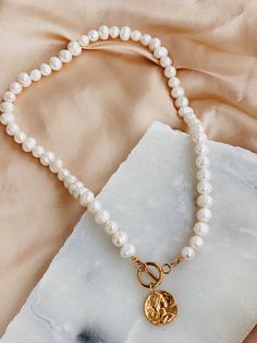 'Chloe' - a modern take on a classic pearl. Beautiful freshwater pearls combined with a gold toggle clasp and a 24k gold coin pendant. Pearls are symbolic of wisdom gained through experience. The gems are believed to offer protection, as well as attract good luck and wealth. Pearls are symbolic of the wearer's loyalty, generosity, integrity, and purity. The surface of the pearls may have few bumps and ridges that indicate the natural origin of the pearls. The necklace is approximately 42 cm in l White Pearl Toggle Necklace With Pearl Pendant, Classic Pearl Charm Toggle Necklace, Classic Toggle Necklace With Pearl Charm For Gift, White Pearl Toggle Necklace With Pearl Charm, Gold Pearl Necklace With Toggle Clasp, Gold Toggle Necklace With Pearl Charm, Elegant Gold Toggle Necklace With Pearl Drop, Elegant Gold Toggle Necklace With Pearl Charm, Gold Pearl Toggle Necklace With Pearl Drop