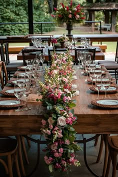 a long table set with place settings and flowers