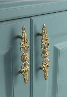 two gold handles on a blue cabinet door