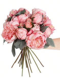 a bouquet of pink peonies is being held by someone's right hand