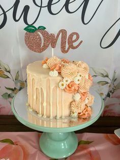 a cake with an apple on top is sitting on a table next to a sign that says sweet one