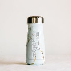 a white and gold water bottle sitting on top of a table