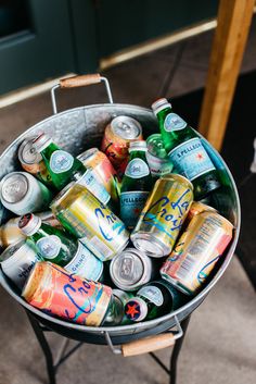 a metal bucket filled with lots of different types of beer cans and cans on top of a table