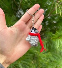 a hand holding a small keychain with a penguin on it