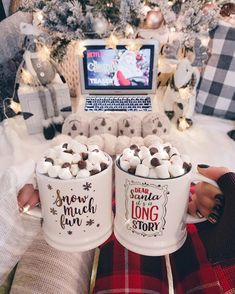 two mugs filled with hot chocolate sitting in front of a laptop