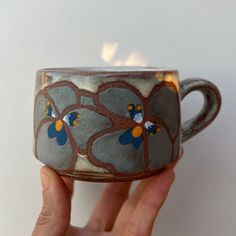 a hand holding a cup with flowers painted on it