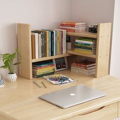 a laptop computer sitting on top of a wooden desk next to a bookshelf