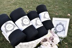 a basket filled with black and white towels next to a framed picture on the grass