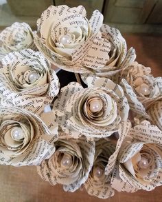 a bouquet of paper flowers made from old book pages with pearls in the center, sitting on a table