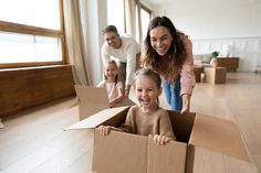 a woman and two children are in a cardboard box on the floor with their parents