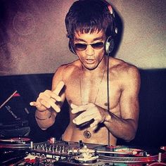 a shirtless man wearing headphones and holding a dj's turntable in front of his face