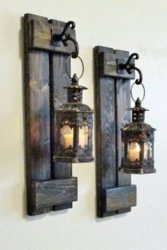 two wall mounted lanterns are hanging on the wall next to each other with candles in them