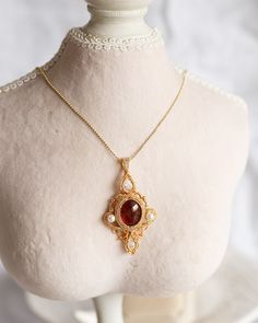 An artisan-made 14K gold-filled pendant, with a Garnet cabochon and faced cubic, is carefully hung from ball chain with a lobster clasp. This captivating pendant, boasting artwork of incomparable skill and a magnificent combination of red Garnet with an orange hue and translucent red Cubic, offers a perfect juxtaposition of poise and dynamism, making it an elitist piece of jewelry. The length of necklaces is approx. 24". Follow me on Instagram: @cubic_jewels Yellow Gold Cabochon Teardrop Pendant Necklace, Gold Square Pearl Pendant Jewelry, Gold Square Pendant Jewelry With Pearl, Gold Pendant Necklace With Cabochon, Gold Cabochon Pendant Necklace, Yellow Gold Medallion Necklace With Cabochon, Gold Cabochon Teardrop Pendant Jewelry, Gold Cabochon Teardrop Pendant, Elegant Teardrop Pendant Cabochon Necklace