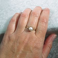 Classic and elegant, this vintage style pearl engagement ring exudes a timeless elegance with a simple band of gold set with a glowing pearl in a crown of hearts. Hand-wrought from recycled 14kt gold, a slim gold band holds a 6.5-7mm cultured creamy white freshwater pearl in a detailed 14kt gold filigree heart-crown setting. Pearl engagement rings are not only unique, but hold a special meaning as pearls symbolize wisdom, purity, harmony and loyalty. This ring would also make a lovely gift for o Timeless Pearl White Pearl Ring For Anniversary, Elegant Pearl Drop Ring For Anniversary, Classic White Pearl Ring With Charm, Classic Pearl White Ring For Promise, Classic White Pearl Ring With Pearl Charm, Classic White Pearl Ring With Drop Detail, Anniversary Rings In Pearl White With Pearl Charm, Timeless Pearl Drop Rings, Anniversary Pearl White Rings With Pearl Charm