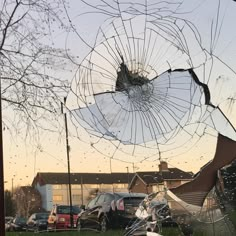 a broken glass window on the side of a building with cars parked in front of it