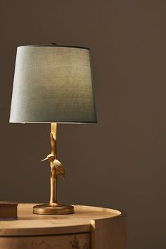 a lamp that is sitting on top of a wooden table in front of a brown wall